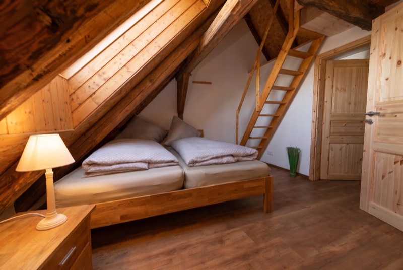 Doppelbett unter holzverkleideter Dachschräge
