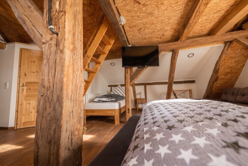 Zimmer mit mächtigem Holzpfosten, Bett und Fernseher am Balken