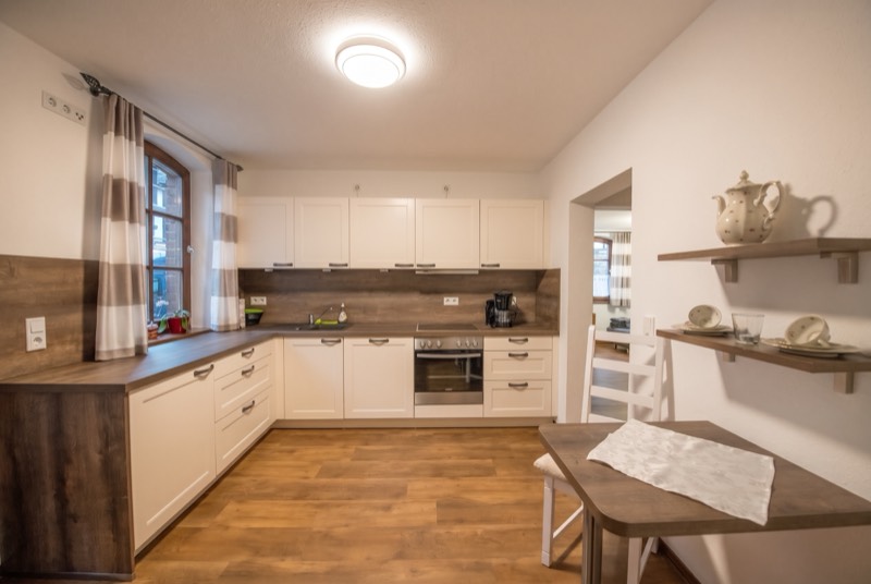 Helle Einbauküche mit Herd, Backofen und Esstisch
