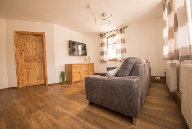 Wohnzimmer mit Sofa, Fernseher und Holzkommode