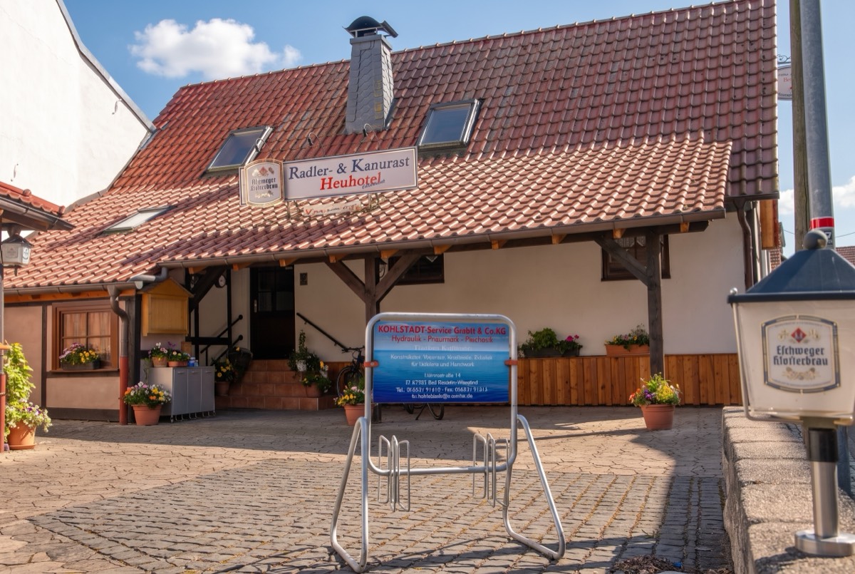 Eingang der Radler- und Kanurast Heuhotel mit Schild und Fahrradständer vor dem Haus