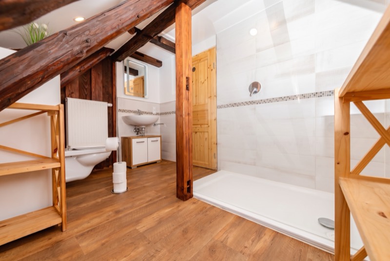 Helles Bad mit großer Dusche, Waschbecken und WC unter Dachbalken
